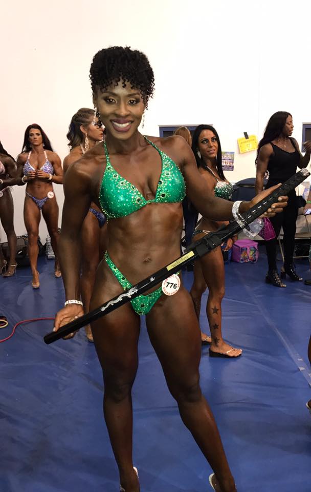Competitor in green suit backstage holding prop